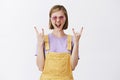 Rock n roll lives forever. Portrait of amazed excited beautiful female with fair hair in sunglasses and yellow overalls