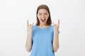 Rock n roll lives guys. Portrait of excited joyful european fair-haired woman in blue t-shirt, showing gestures with