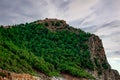 A rock overgrown with coniferous forest with the ancient wall of the Alanya Castle Turkey at the top on a summer-autumn cloudy Royalty Free Stock Photo