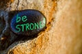 A rock painted black with the message Be STRONG