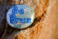 A rock painted silver and light blue stating Be Brave