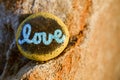 A rock painted yellow with the word love written