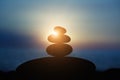 Rock pebble pyramid silhouette at sunset light, zen stones on sea beach