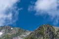 Rock ridge with snow and stone placers under blue sky. Royalty Free Stock Photo