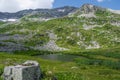 Rock ridge with snow and stone placers under blue sky. Summer trip to mountain valley. Atmospheric alpine landscape Royalty Free Stock Photo