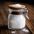 Rock salt in a glass jar with a wooden lid - a salt shaker on a wooden table. Blurred background, close-up. AI generated