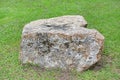 Rock seat on green grass garden. Natural stone chair in park Royalty Free Stock Photo