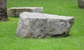 Rock seat on green grass garden. Natural stone chair in park Royalty Free Stock Photo