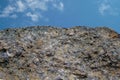 Rock or stone on blue sky with clouds background. Granite crouan rim or pick edge like cliff or mountain. Geology mineral texture