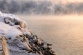 Rock stones covered with ice, snow and icicles on the Yenisei river bank during winter foggy dawn Royalty Free Stock Photo