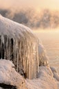 Rock stones covered with ice, snow and icicles on the Yenisei river bank during winter foggy dawn Royalty Free Stock Photo