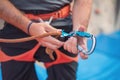 Rock wall climber wearing safety harness and climbing equipment indoor, close-up image