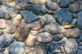 Rock wall made of colorful river rock, sun dappled, as an abstract textured background