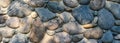 Rock wall made of colorful river rock, sun dappled, as an abstract textured background