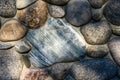 Rock wall made of colorful river rock, sun dappled, as an abstract textured background