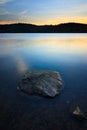 A rock in the water with sunset