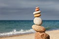 Rock zen pyramid of colorful pebbles on a sandy beach on the background of the sea. Concept of balance, harmony and meditation Royalty Free Stock Photo
