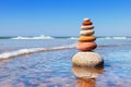 Rock zen pyramid of colorful pebbles standing in the water on the background of the sea. Concept of balance, harmony and Royalty Free Stock Photo