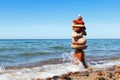 Rock zen pyramid of colorful pebbles standing in the water on the background of the sea. Concept of balance, harmony and Royalty Free Stock Photo