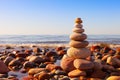 Rock zen pyramid of multi-colored pebbles in the pink rays of the setting sun against the sea. Concept of balance, harmony and Royalty Free Stock Photo