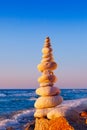 Rock zen pyramid of white stones in the pink rays of the setting sun against the sea Royalty Free Stock Photo