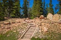 Rock zig zag steps up rocky hillside with pine trees against blue sky at top-destination Royalty Free Stock Photo