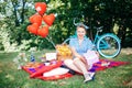 Group of friends at park having fun party. Beautiful girl with a gif in hands on a picnic