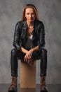 Rocker in black leather jacket posing seated in studio while res Royalty Free Stock Photo