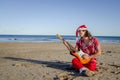 Rocker Guitarist with Long Hair Dressed in Red with a Santa Claus Hat Playing His Instrument Passion Royalty Free Stock Photo