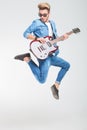 Rocker jumping one side in studio while playing guitar Royalty Free Stock Photo