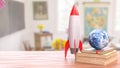 Rocket and Earth Globe on Books in Bright Classroom Setting 3d render Royalty Free Stock Photo