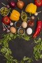 Rocket and spinach, eggs and tomatoes, yellow and red peppers, garlic, olives on black Royalty Free Stock Photo