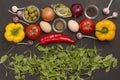 Rocket and spinach, eggs and tomatoes, yellow and red peppers, garlic, olives on black Royalty Free Stock Photo