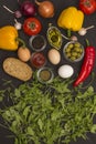 Rocket and spinach, eggs and tomatoes, yellow and red peppers, garlic, olives on a black background Royalty Free Stock Photo