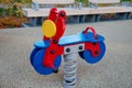 Rocking chair on a blue and red metal spring made of natural wood in the form of a scooter on a playground Royalty Free Stock Photo