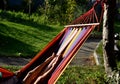 Rocking chair, hammock with wooden support among the trees in the garden. view of naked hairy white legs of a rocking man, striped Royalty Free Stock Photo