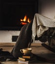 Rocking chair with knit rug, books and cup of tea or coffee before fireplace Royalty Free Stock Photo