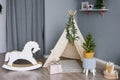 Rocking horse for children made of phoners and cardboard in a children`s room decorated for Christmas or New Year, a wigwam tent