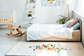 Rocking horse near bed with white bedding and toy blocks on carpet Royalty Free Stock Photo