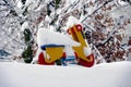 Rocking motorcycle on a spring, wooden toy in red and yellow  in garden in winter, with  snow covered . Royalty Free Stock Photo