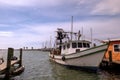 ROCKPORT, TX - 3 FEB 2020: White and green shrimp boat tied by rope to the wooden dock in a marina