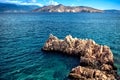 Rocks on cliffs and waves in the ocean, seen from a beach. Calm water, clear sky and waves on a sunny summer day