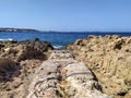 Rocks on the coast of Ibiza island, beautiful sea with mountains and islands in the background