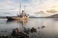 Rocks and a completely calm sea in the foreground with a ship aground with mountains in the background, Ushuaia Royalty Free Stock Photo