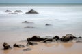 Rocks covered with marine foam. Long exposure on the coast. Silk effect in sea water