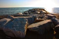 Rocks lined up on the sea water in front of the beach at sunset