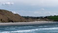 Rocks on the ocean shore on a sunny day. Clear blue sky. Seascape. Beautiful coastline. Brown and green hills beside body of water Royalty Free Stock Photo