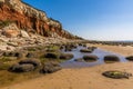 Rocks and rock pools at the base of the white, red and orange stratified cliffs at Old Hunstanton, Norfolk, UK Royalty Free Stock Photo