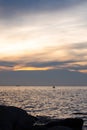 Rocks on the sand and fishermen in small fishing boats On the sunset background,silhouette