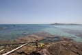 Rocks on the sea with island in the background and boat. Royalty Free Stock Photo